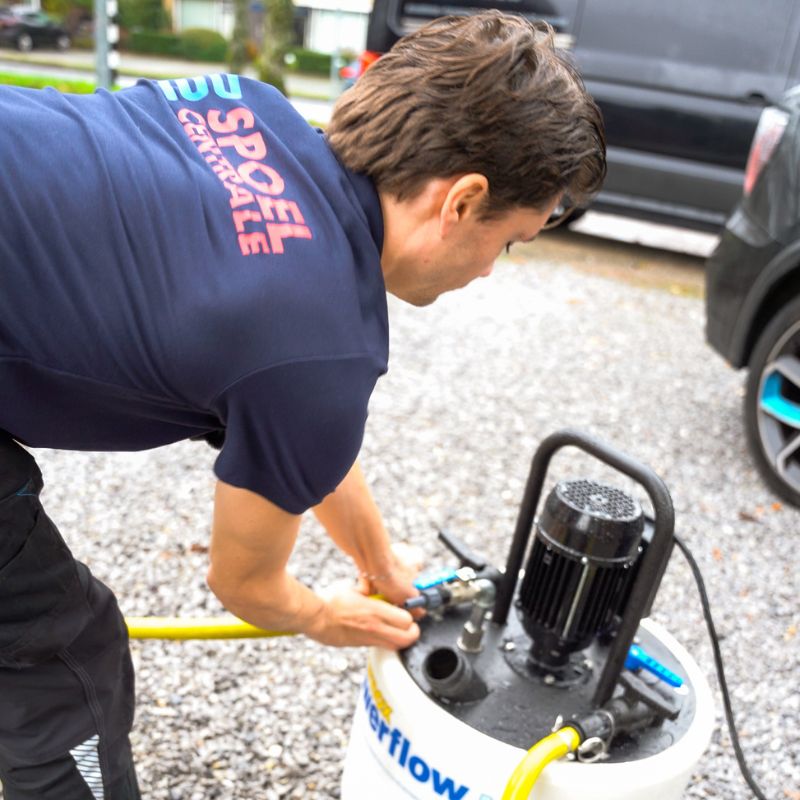 Professionele specialist die vloerverwarmingsleidingen reinigt met spoelinstallatie